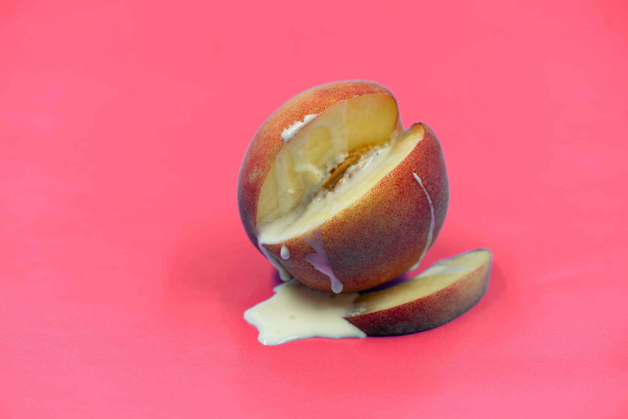 A cut-open peach with milk dripping out