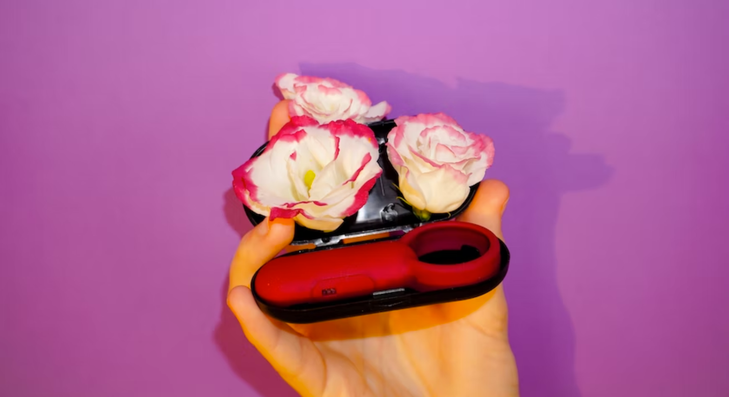 A hand holding a case with a bullet vibrator and flowers