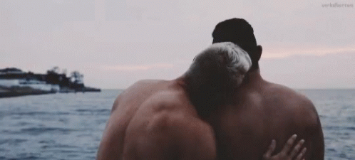 A man caressing another’s back in front of the ocean