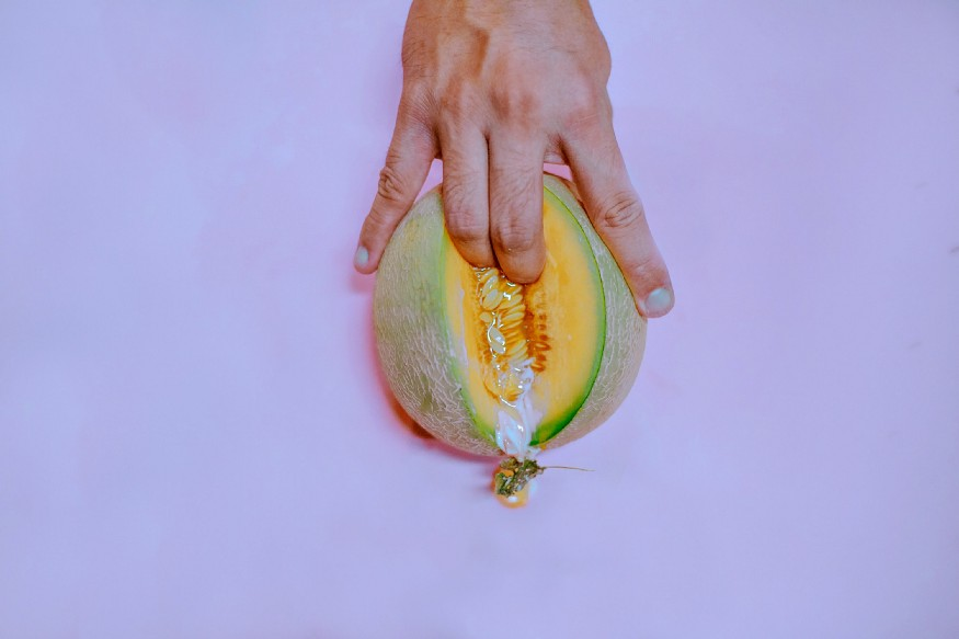 Fingers inserting an open melon