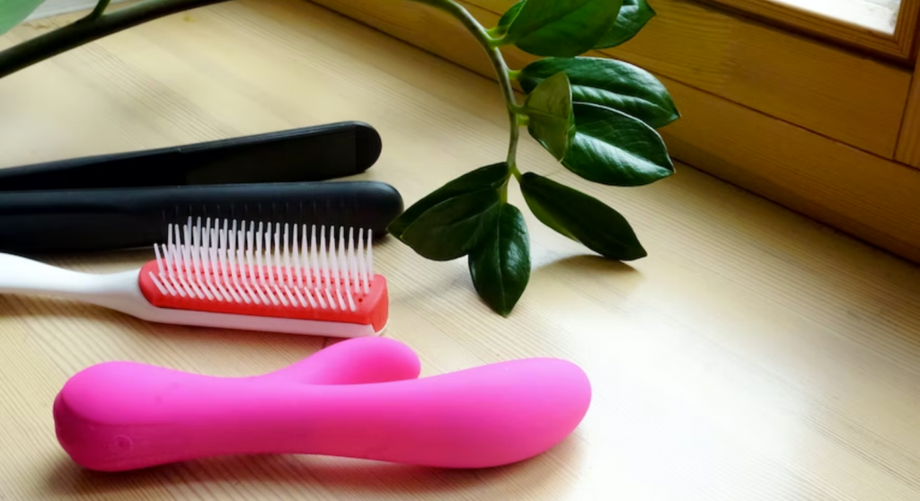 A vibrator next to a comb and a hair straightener