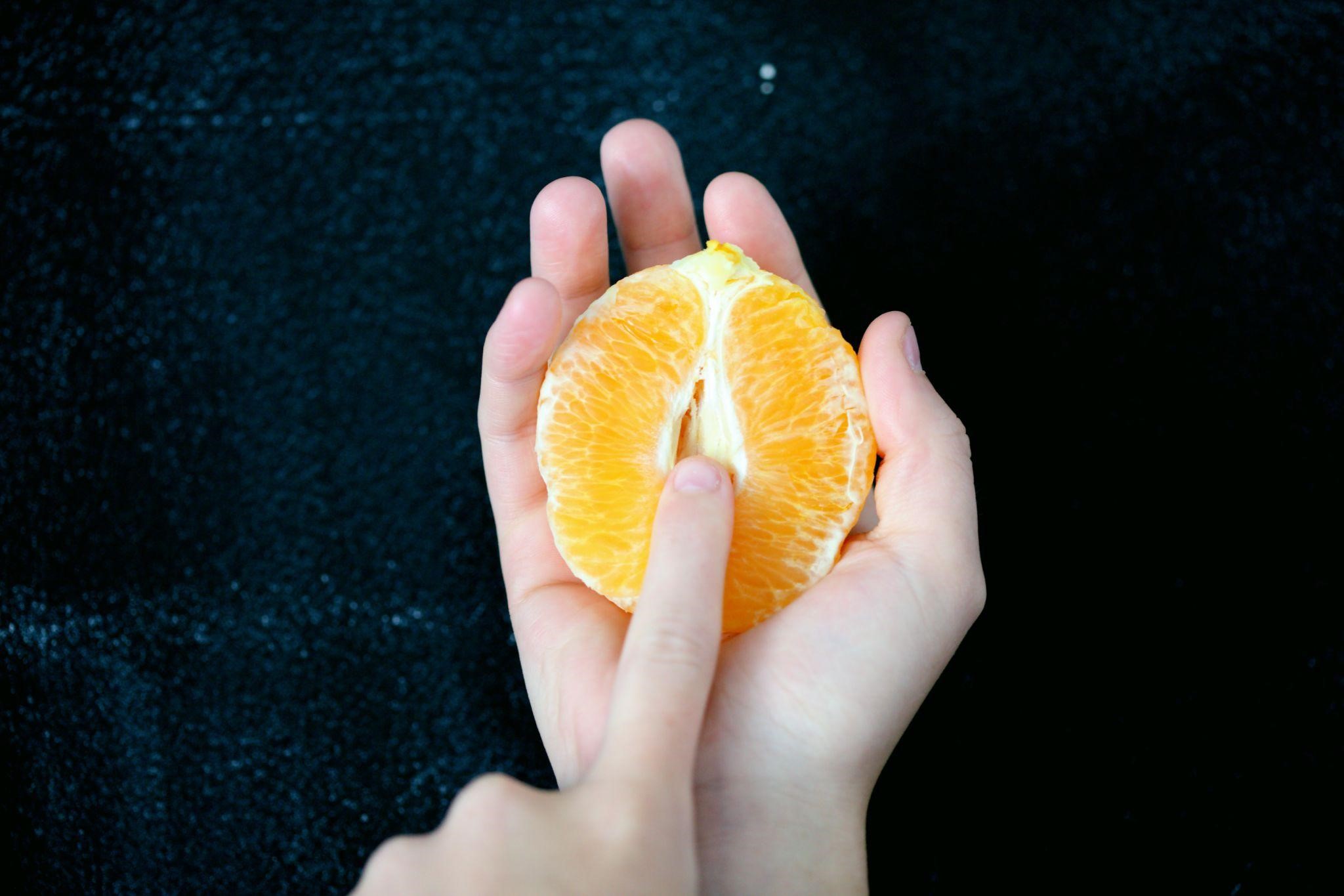 A finger caressing an orange.